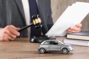 Attorney reviewing documents beside a model car and gavel, representing cases handled by a Longmont car accident lawyer.