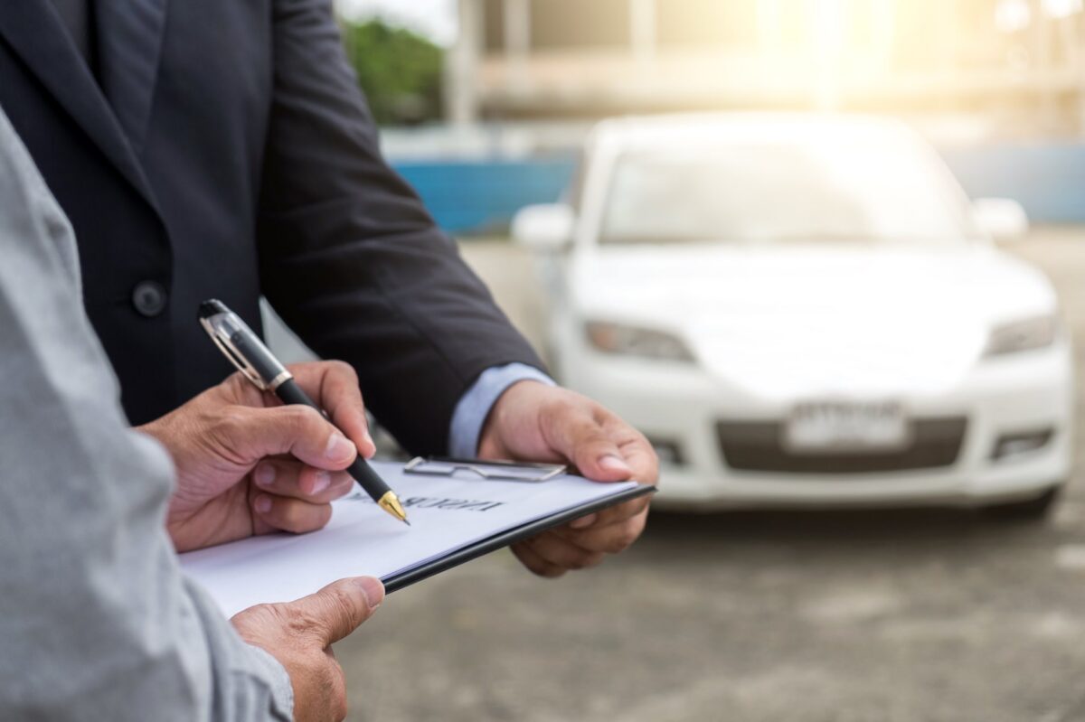 Zoomed in picture of one person holding a clipboard and another person signing paperwork on it