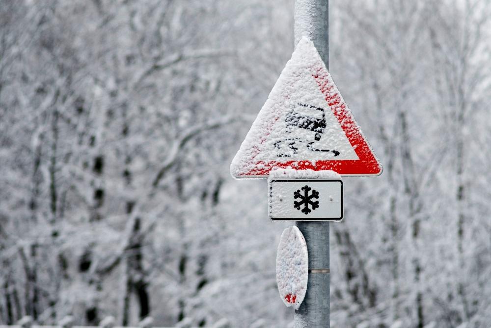Snowy slippery road warning sign | slip and fall lawyer | The Law Offices of Edward Smith LLC