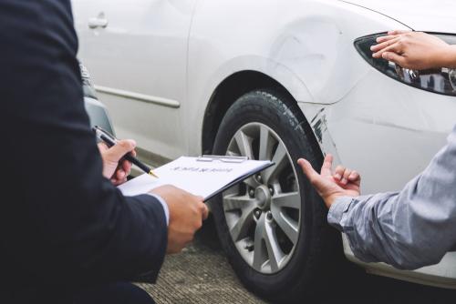 Two men inspecting a dented white car | car accident lawyer | The Law Offices of Edward Smith LLC
