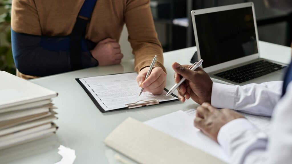 Man in an arm sling signing a form | personal injury lawyer | The Law Offices of Edward Smith LLC