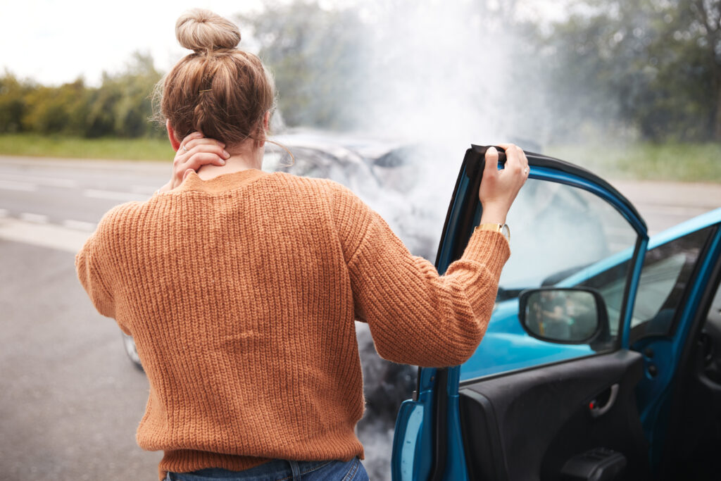 Woman holding her neck by a crashed car | car accident lawyer | The Law Offices of Edward Smith LLC