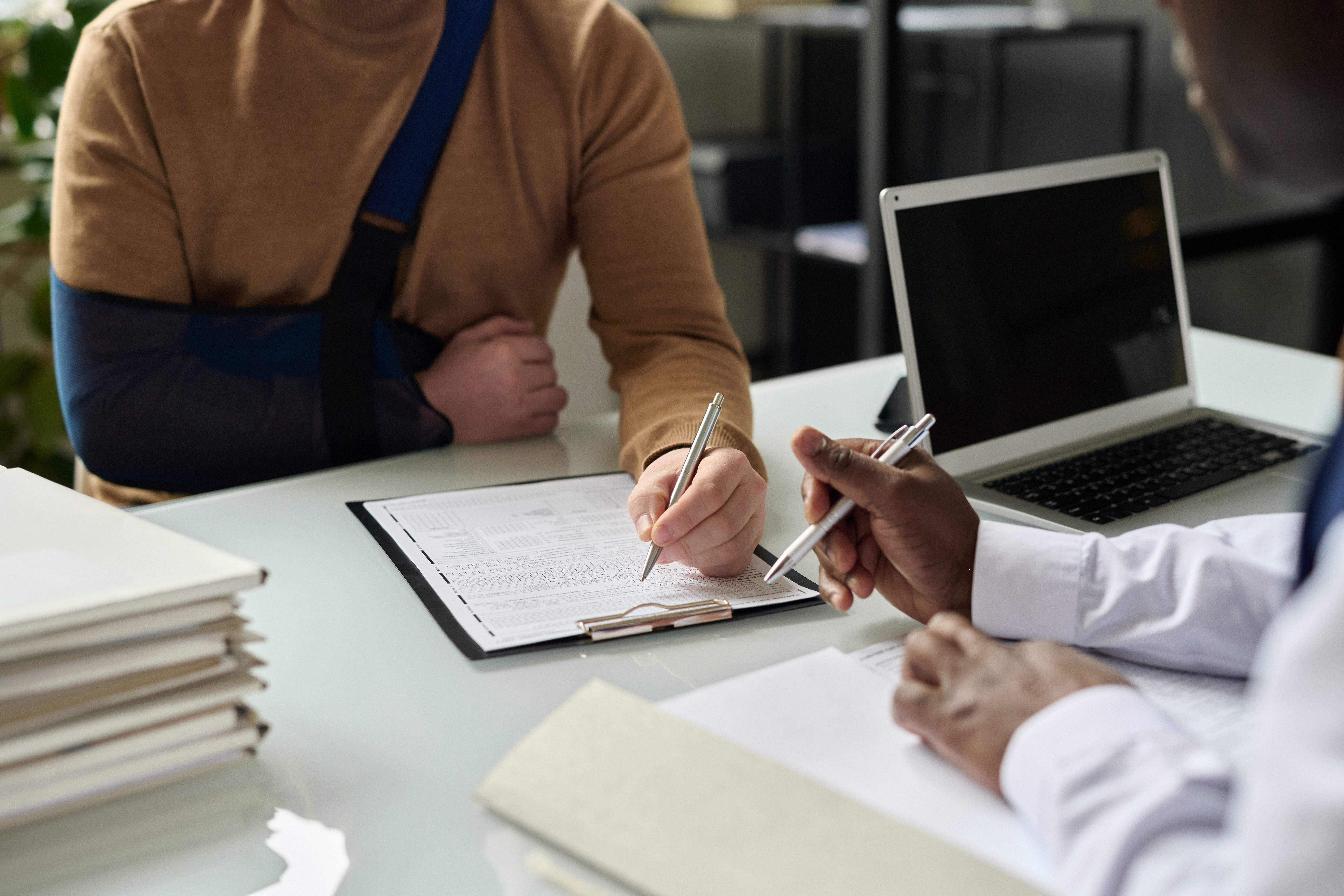 Man in an arm sling signing a form | personal injury lawyer | The Law Offices of Edward Smith LLC